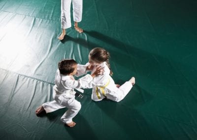 Children (5-7 years) practicing Jiu-Jitsu, instructor watching. Brazilian jiu-jitsu is a martial art, self defense system and combat sport.